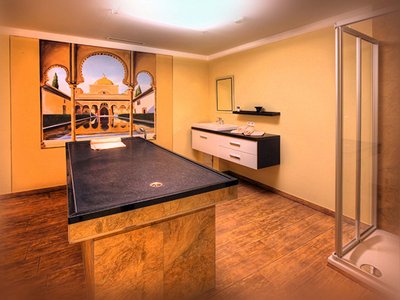 Wellnesshotel in Sölden: Hotel Sunny Wellnessraum mit Massagetisch, Dusche und orientalischem Wandbild
