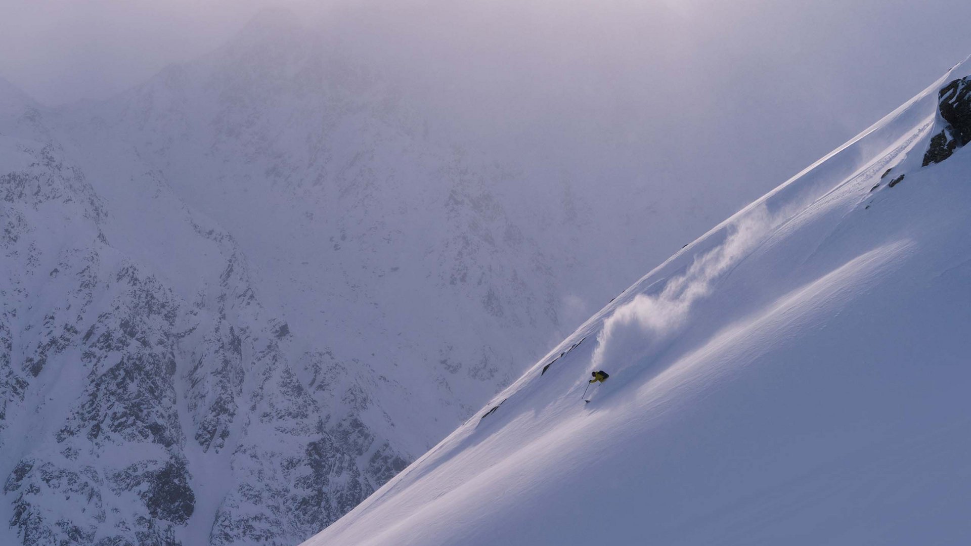 Ausflugsziele in Sölden gesucht? Skifahrer fährt einen steilen, schneebedeckten Berg bei Nebel.