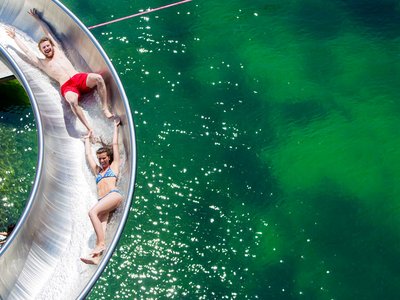 Family hotel in Sölden: Hotel Sunny Sölden Two people sliding down a water slide into a lake holding hands