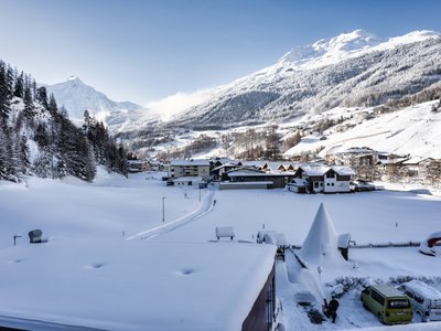 Ausflugsziele in Sölden gesucht? Verschneites Bergdorf mit Häusern und schneebedeckten Alpen im Hintergrund