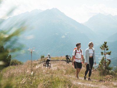 Ausflugsziele in Sölden gesucht? Wanderer und Mountainbiker auf einem Bergpfad vor alpiner Bergkulisse