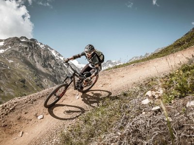 Bikehotel in Sölden: Hotel Sunny Mountainbiker fährt auf kurvigen, bergigen Pfad bei klarem Himmel