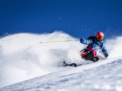 Dein 4-Sterne-Hotel im Ötztal Skifahrerin fährt im Tiefschnee bei strahlend blauem Himmel