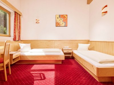 Family hotel in Sölden: Hotel Sunny Sölden Twin room with red carpet, wooden furniture, and sunlight through the window